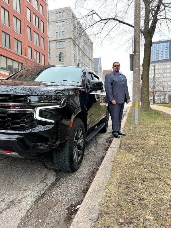 Khaled Aly, founder and owner of Pharaoh's Transportation, beside a black luxury SUV